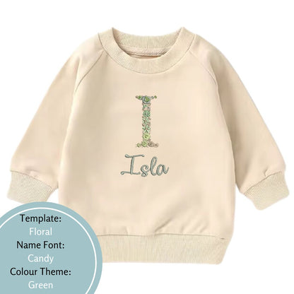 beige baby and toddler crewneck embroidered with a floral name design using a green colour theme