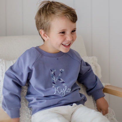 blue baby and toddler crewneck embroidered with a dinosaur name design using a blue colour theme