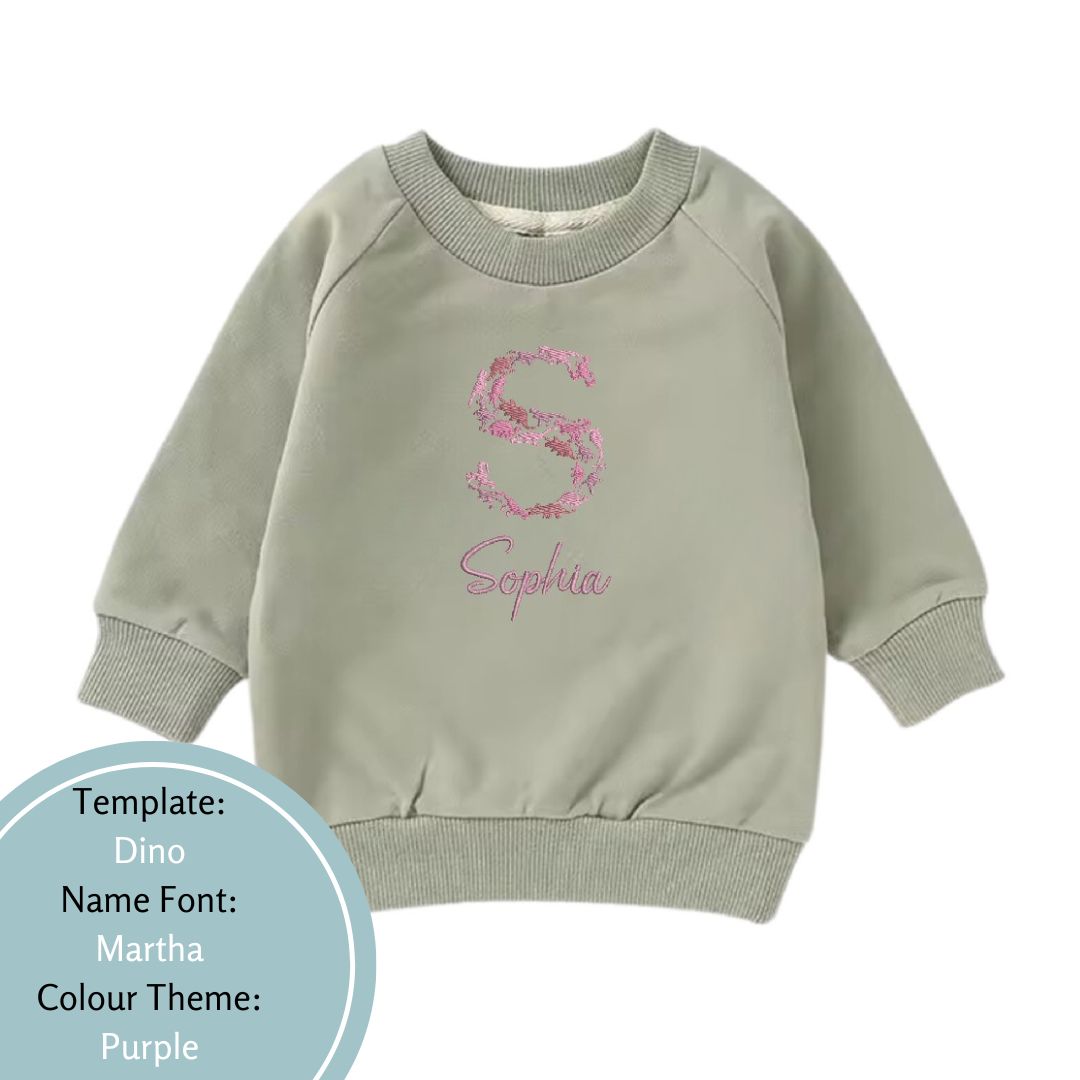 khaki green baby and toddler crewneck jumper embroidered using a dinosaur theme with a purple colour theme