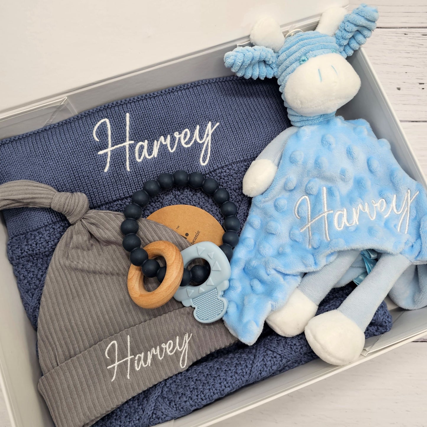 Gift box with diamond knit blanket, blue comforter, grey beanie and silicone teether