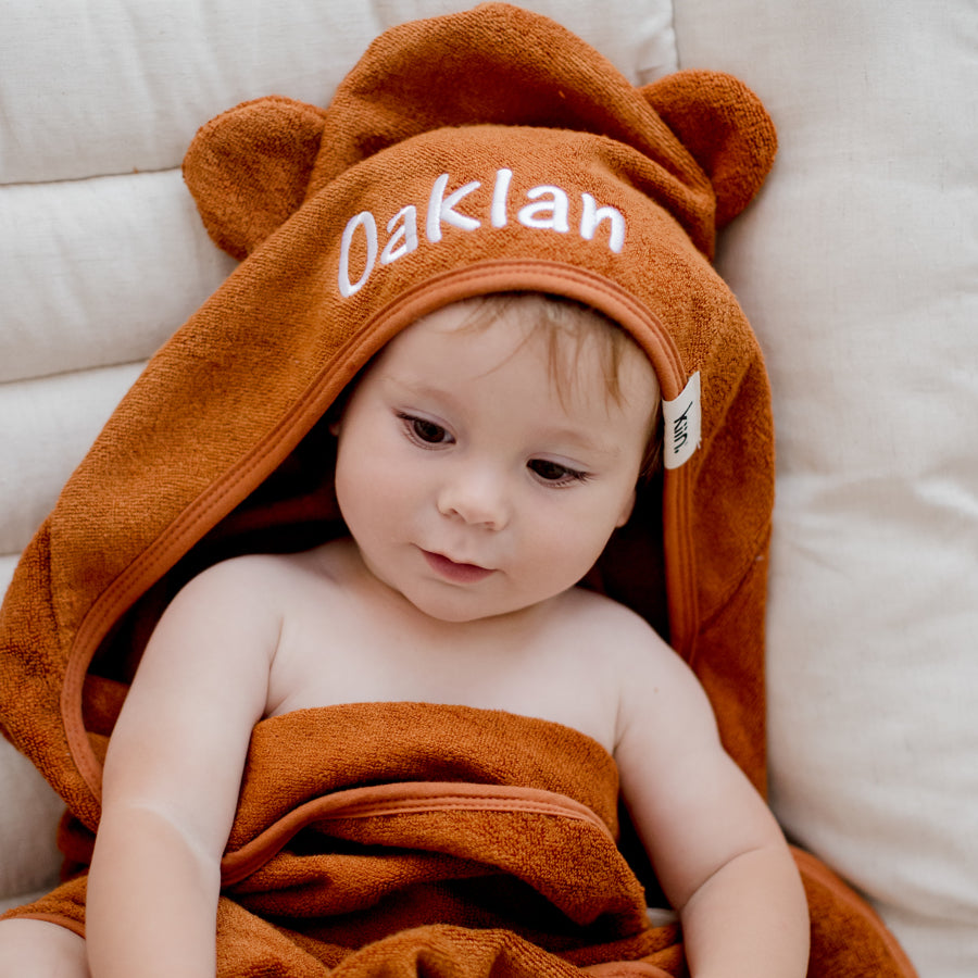 child wearing tan brown hooded bath towel newborn gift personalise with baby name embroidery